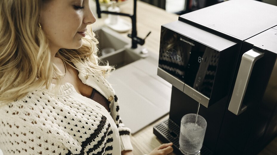 Frau steht vor Osmoseanlage und lässt Wasser heraus