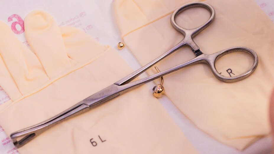 Eine Sterile Piercingnadeln wird ausgepackt, sterile Werkzeuge und Arbeitsmaterialen liegen bereit