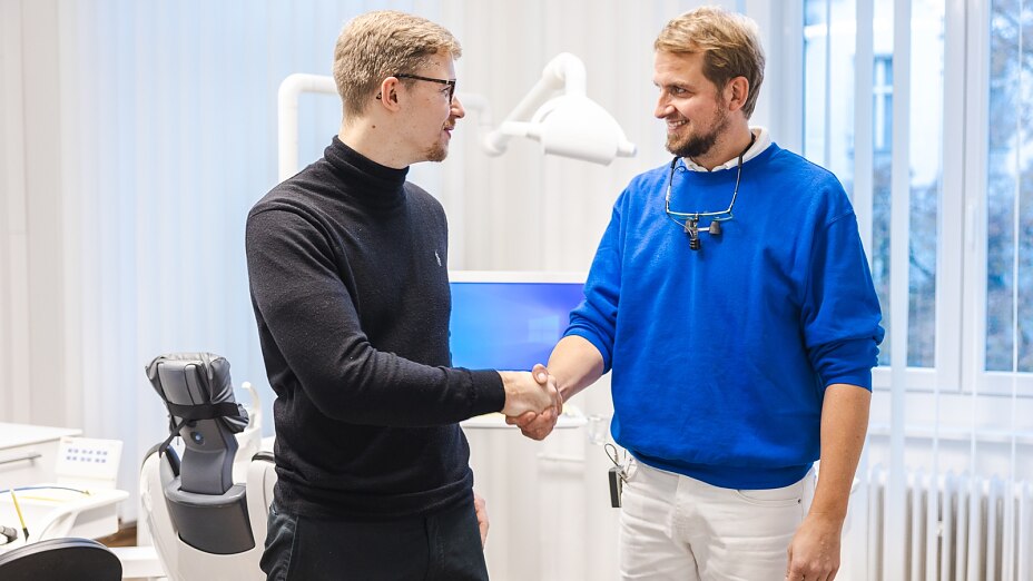 alt="zwei Männer schütteln sich in einer Arztpraxis die Hände"