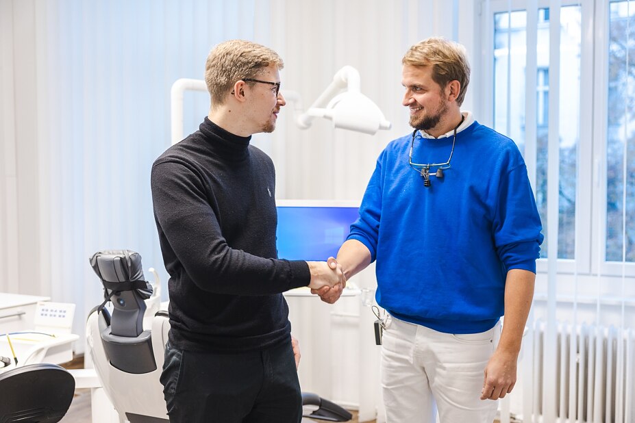 alt="zwei Männer schütteln sich in einer Arztpraxis die Hände"
