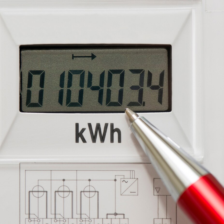 Stromzähler zeigt kWh-Wert, ein Stift deutet auf die aktuelle Verbrauchsanzeige.