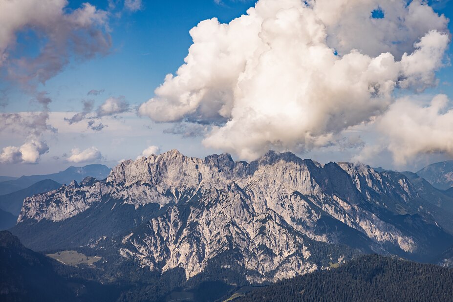 Bergkette angestrahlt von der Sonne mit Bewölkung im Hintergrund