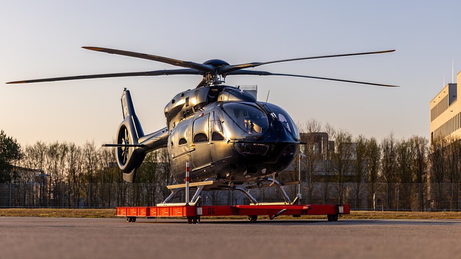 schwarzer VIP Hubschrauber steht auf roter Plattform im Sonnenuntergang