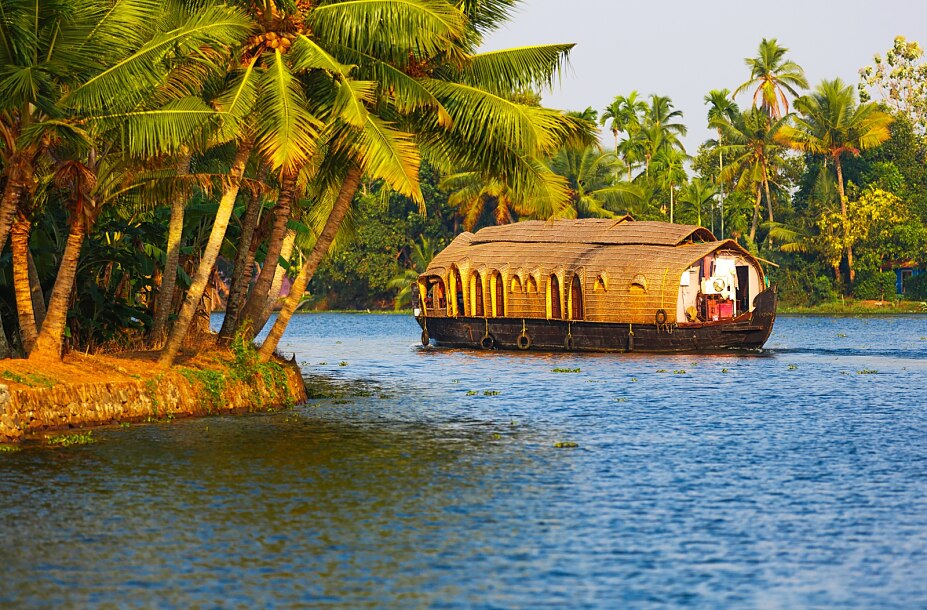 Traditionelles Hausboot auf den Backwaters von Kerala während einer Südindien Reise, umgeben von tropischen Palmen und idyllischen Wasserwegen.