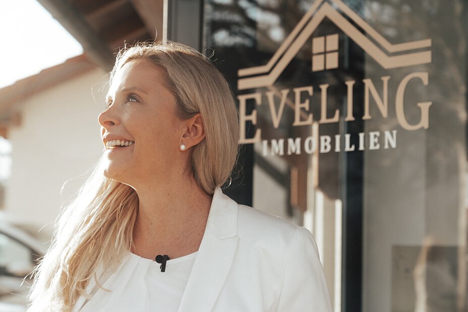 Das Bild zeigt Andrea Gabrisch, Immobilienmaklerin, Inhaberin und Geschäftsführerin von Eveling Immobilien, vor dem Eingang zu ihrem Büro in Grasbrunn.