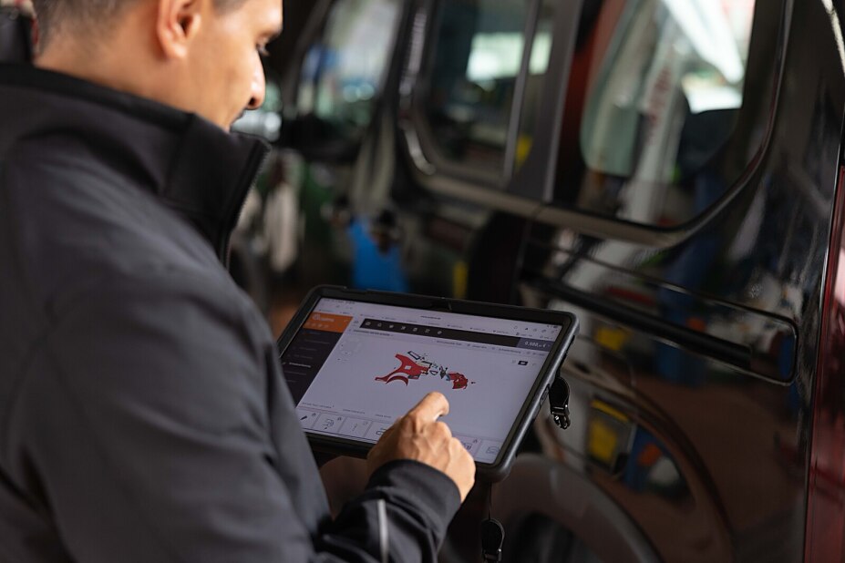 Kfz-Sachverständiger in München dokumentiert einen Fahrzeugschaden mit dem Tablet in der Werkstatt